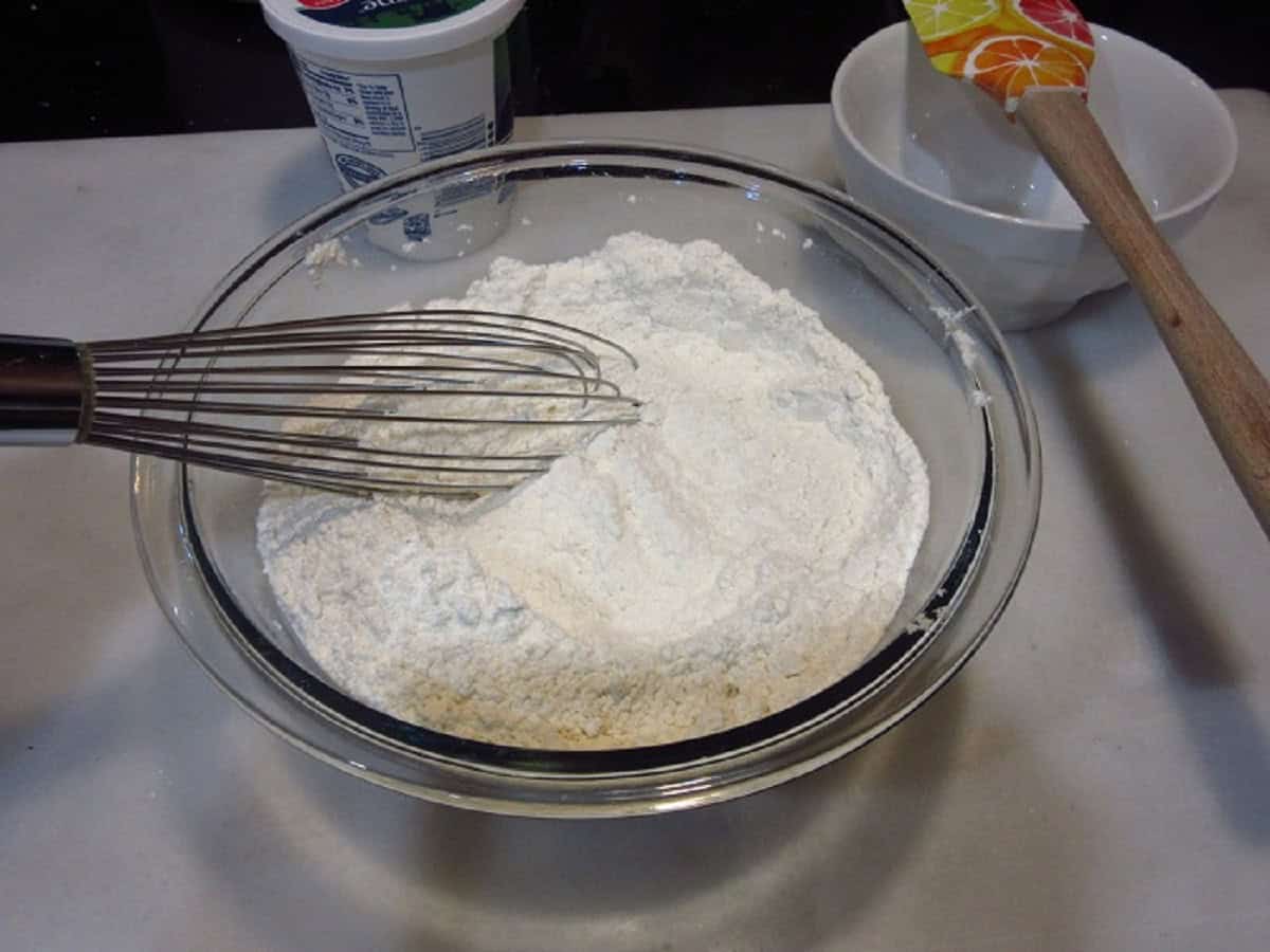 Flour in a glass bowl with a whisk.