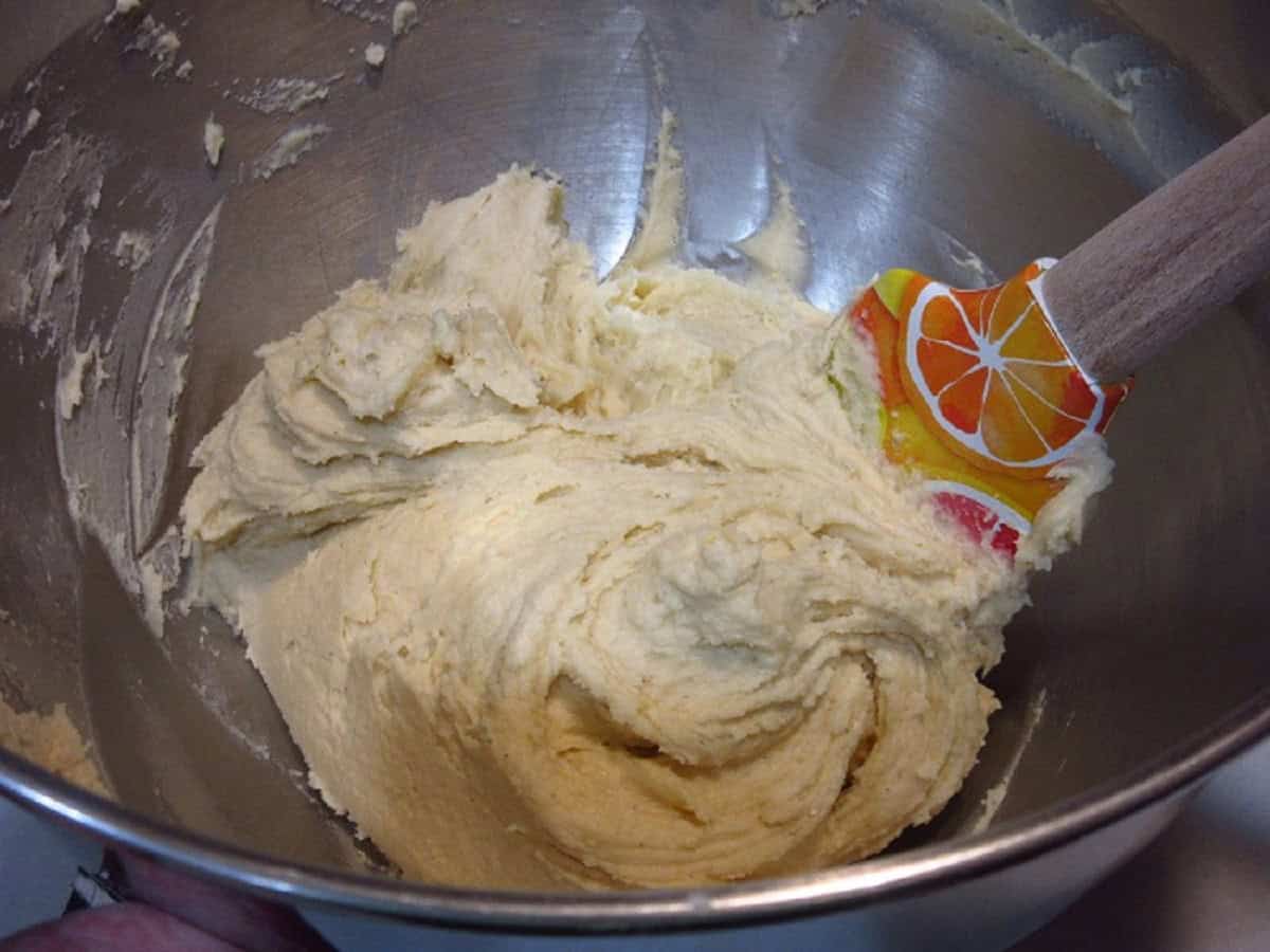 Lemon ricotta cookie dough in a stand mixer bowl with a spatula.