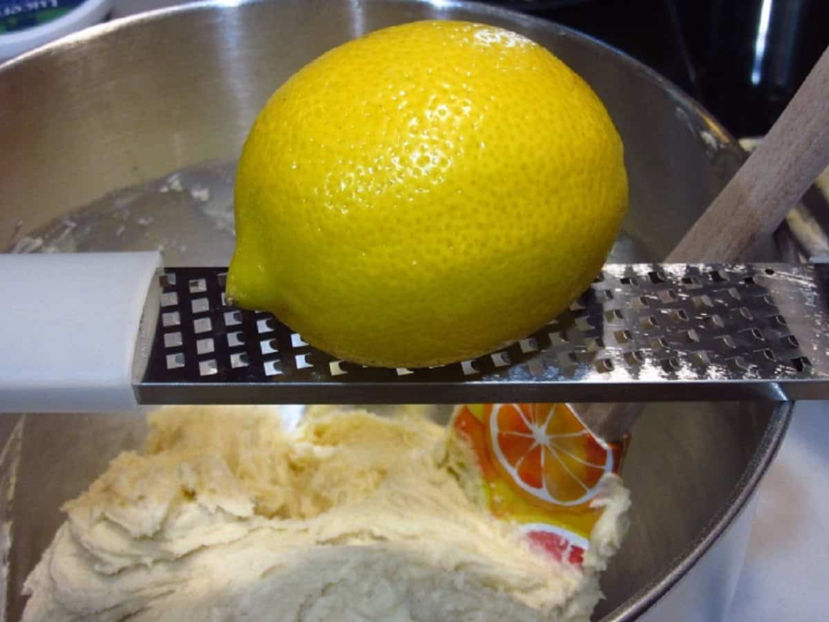 A lemon on a microplane over a bowl of cookie batter.
