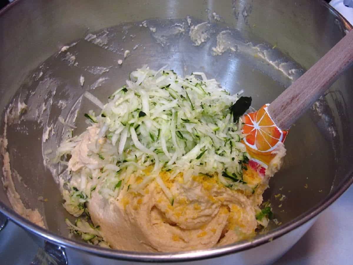 Shredded zucchini and lemon zest in a mixing bowl with a ricotta cookie dough.