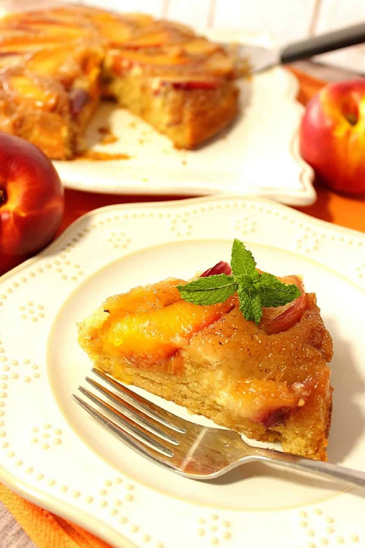 A slice of Nectarine Upside Down Cake on a white plate with a fork.