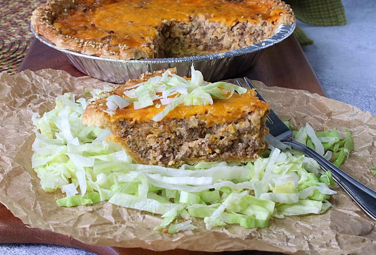 A slice of Big Mac Quiche on a bed of shredded lettuce with a fork.