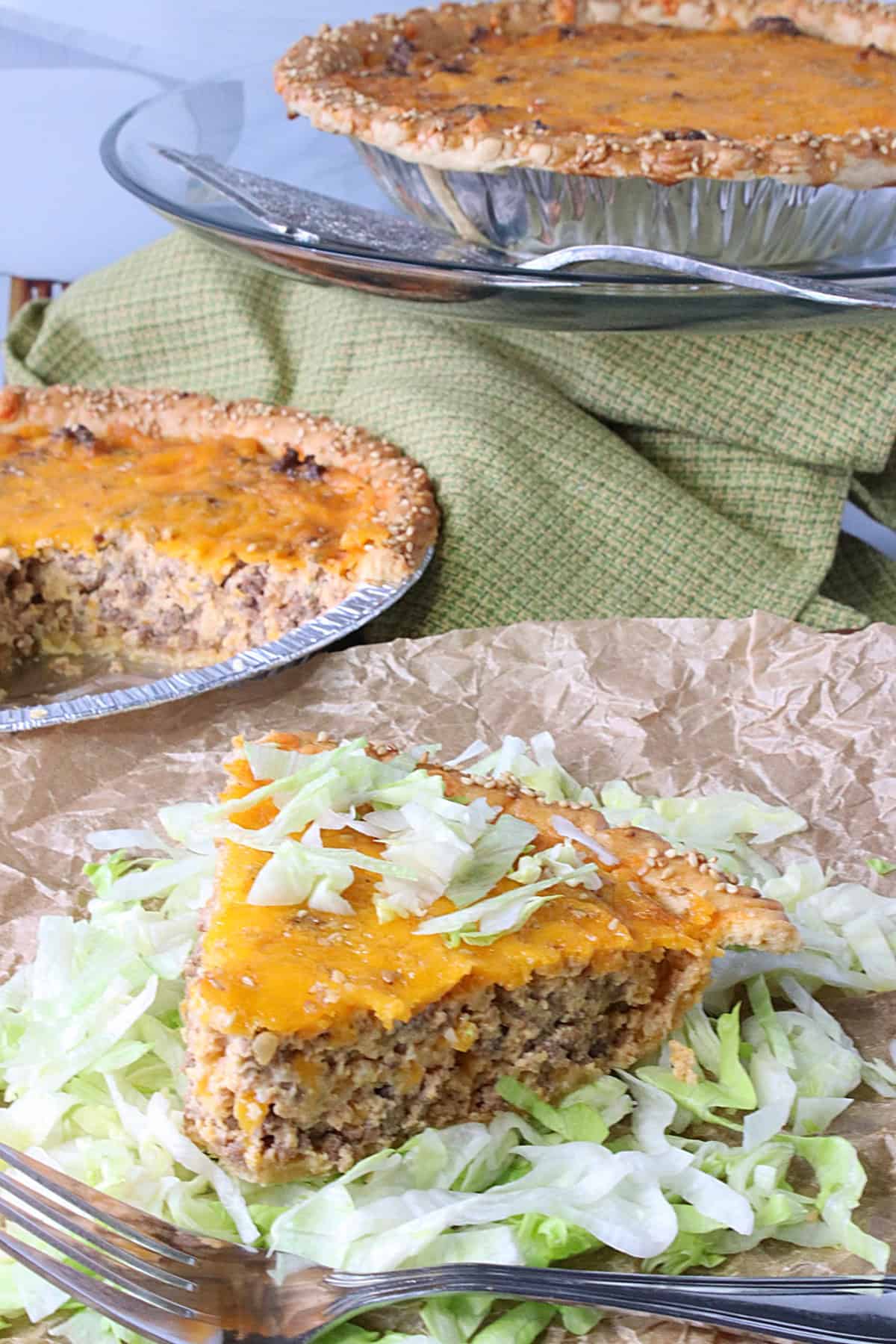 A slice of big mac quiche on parchment paper with shredded lettuce.