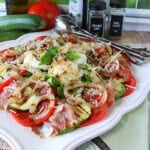A pretty Caprese salad with zucchini and burrata on a square decorative platter.