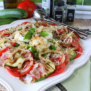 A pretty Caprese salad with zucchini and burrata on a square decorative platter.