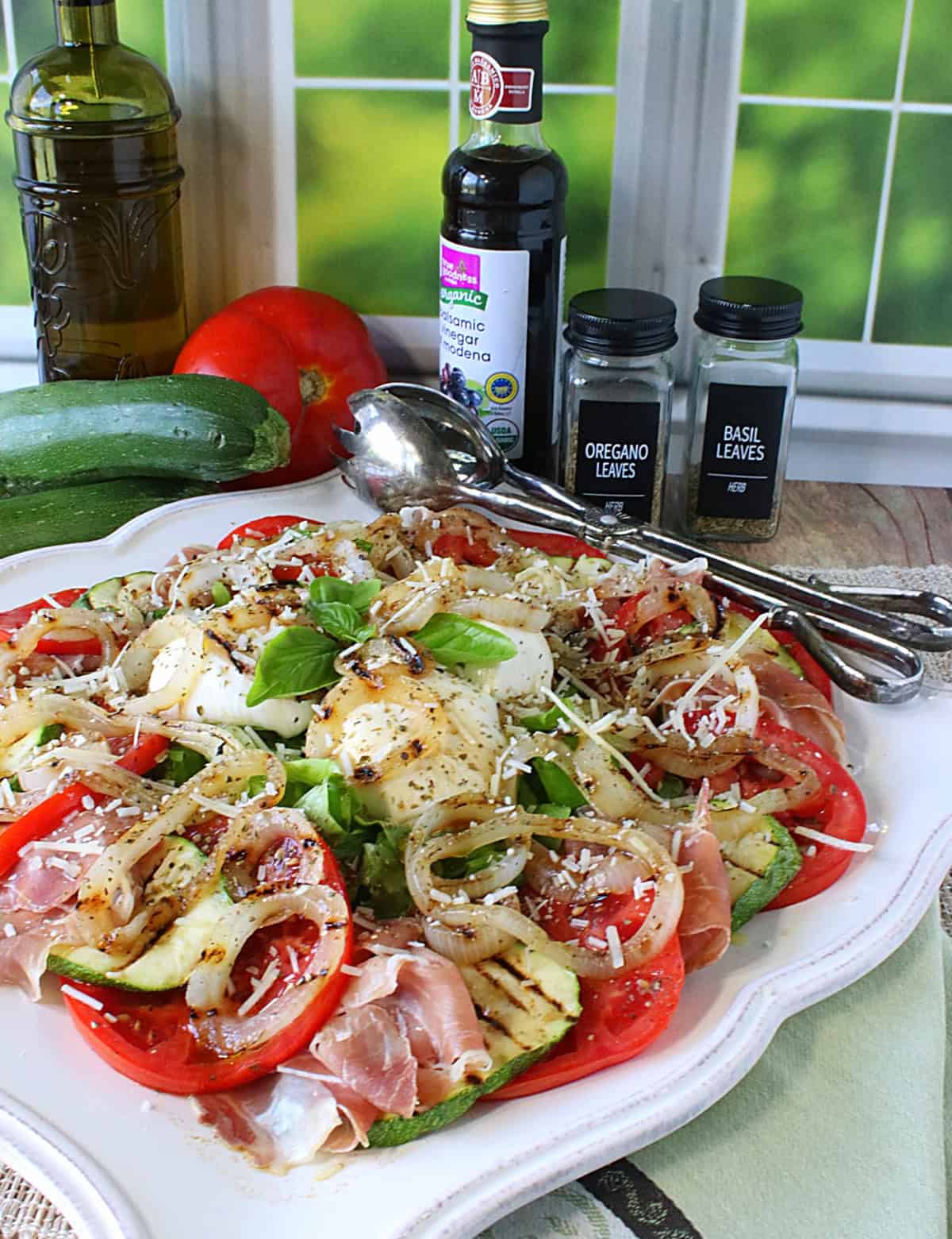 A Caprese salad with grilled vegetables on a pretty square platter.