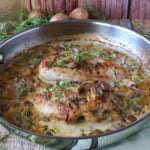 A large silver sauté pan containing Creamy French Tarragon Chicken breasts with mushroom sauce.