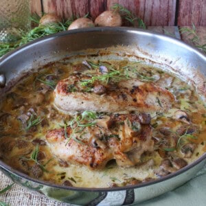 A large silver sauté pan containing Creamy French Tarragon Chicken breasts with mushroom sauce.
