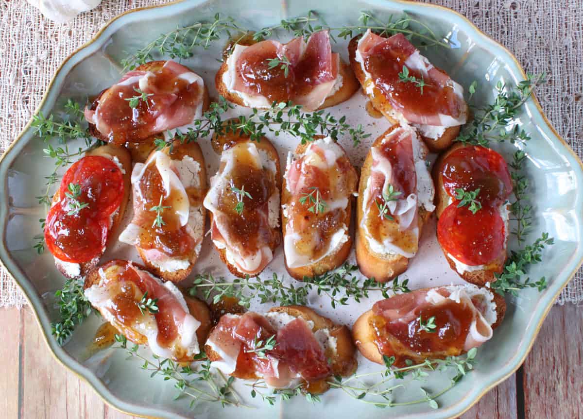 A pretty platter filled with goat's cheese crostini with fig jam and prosciutto.