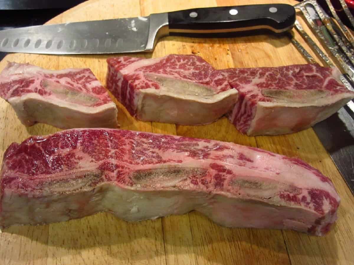 Short ribs on a cutting board with a knife.