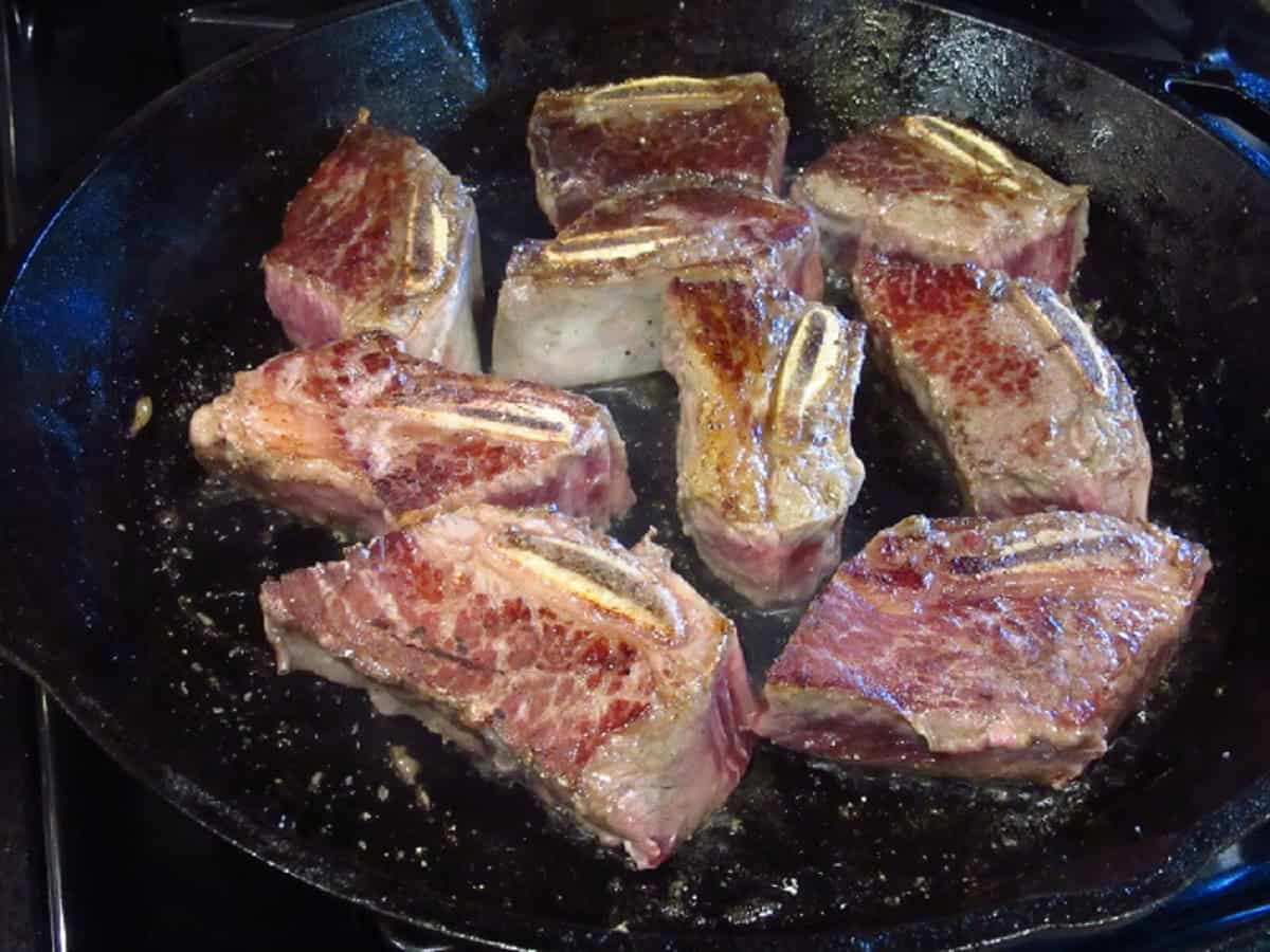 Browning short ribs in a cast iron skillet.