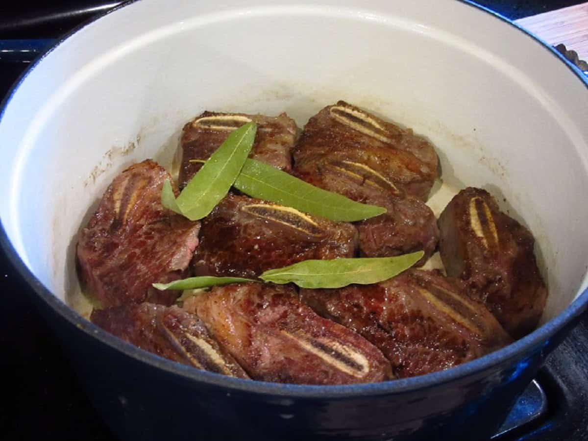 Bay leaves in a pot with browned short ribs.