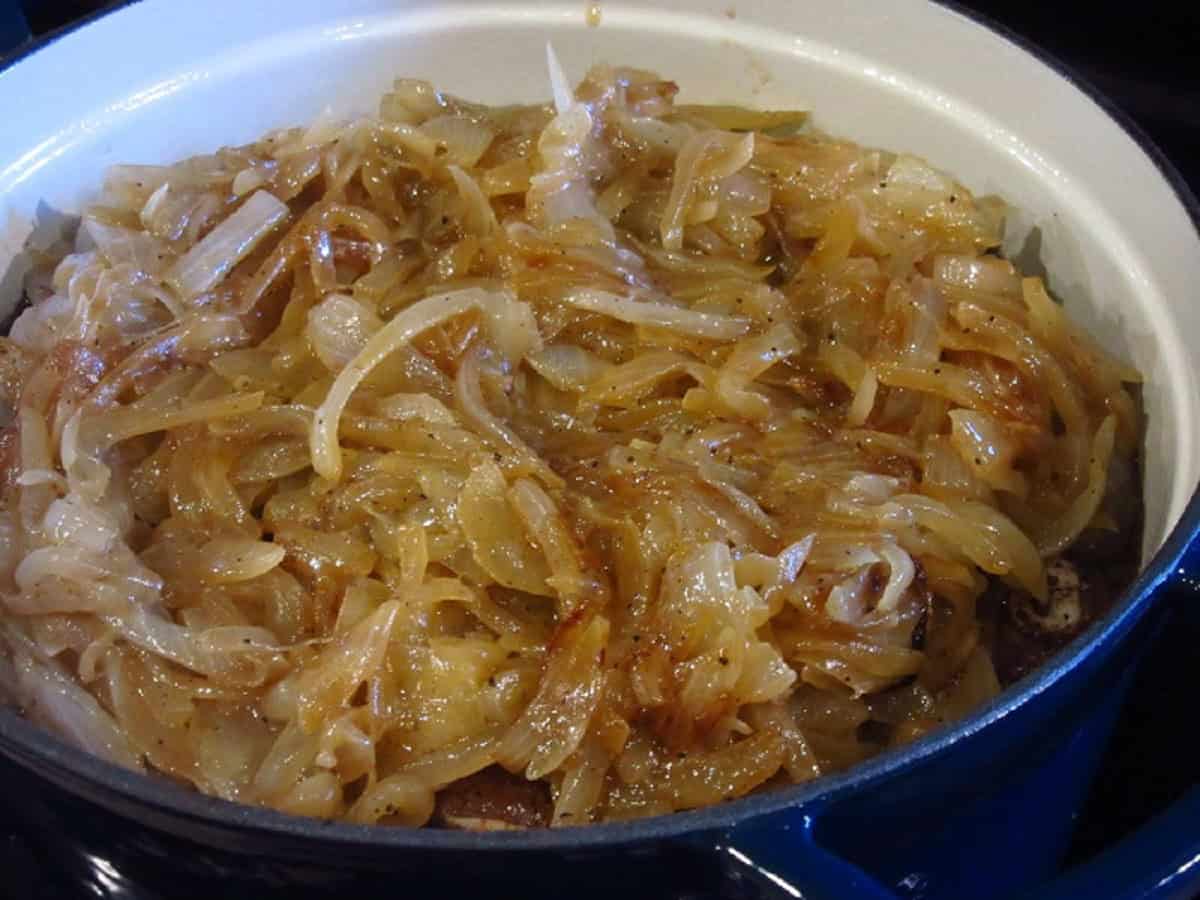Caramelized onions in a blue Dutch oven.