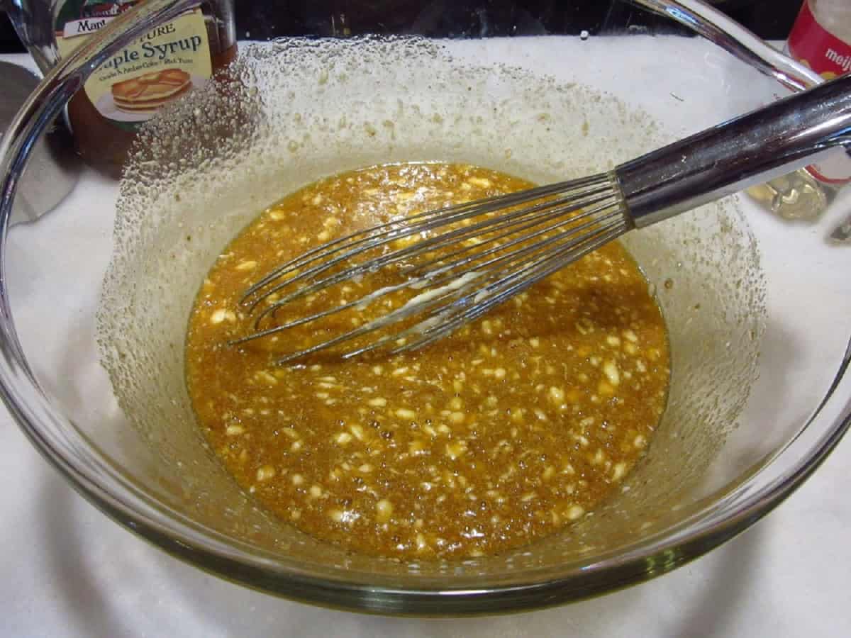 Pecan pie filling in a glass bowl with a whisk.