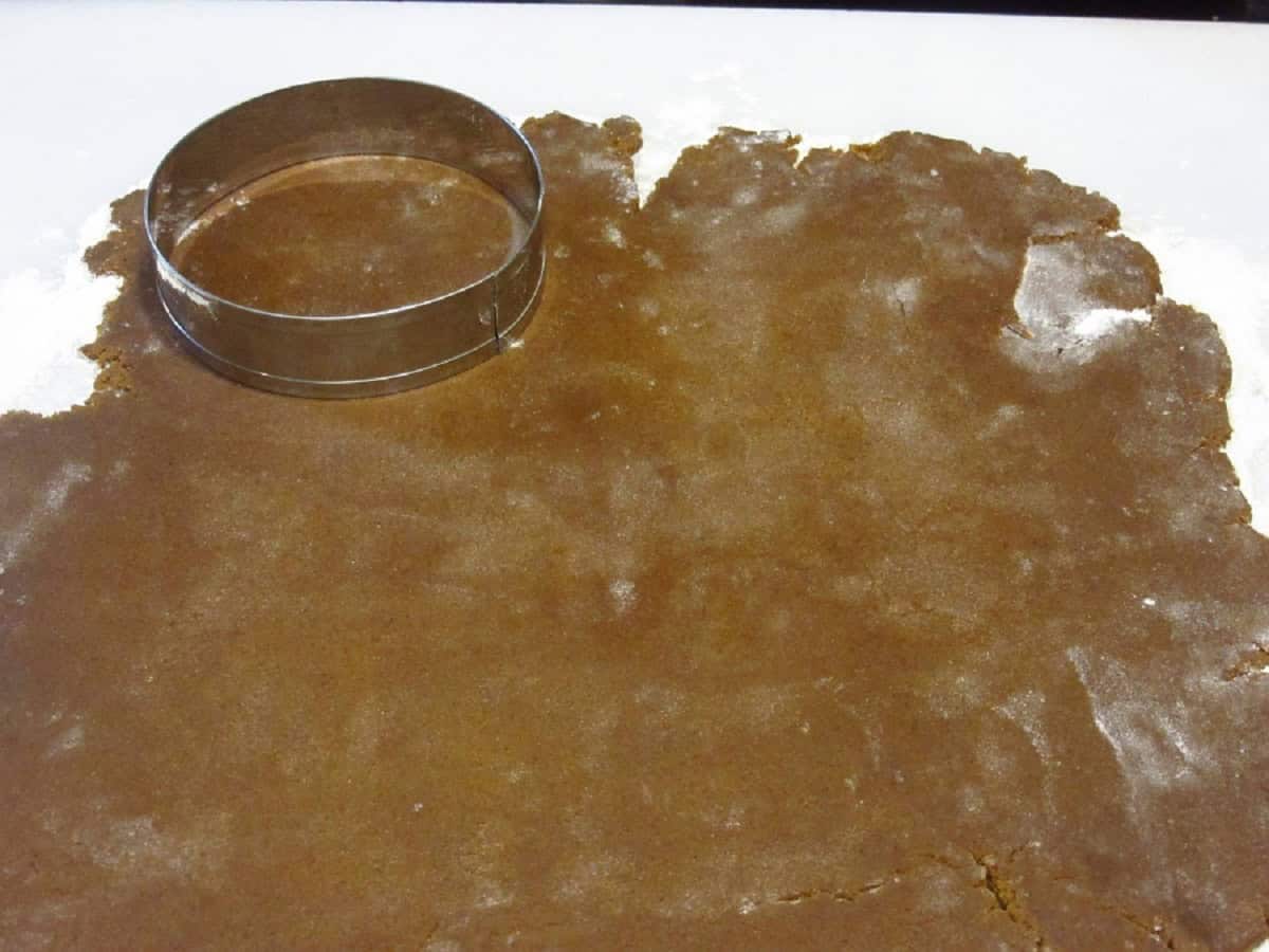 R round cookie cutter on a rolled out piece of cookie dough.