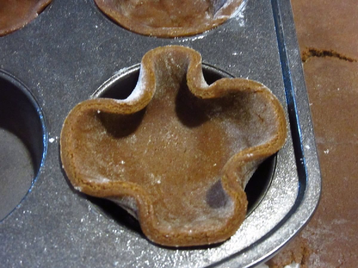 A round disc of gingerbread pie crust before being pressed into a muffin tin.