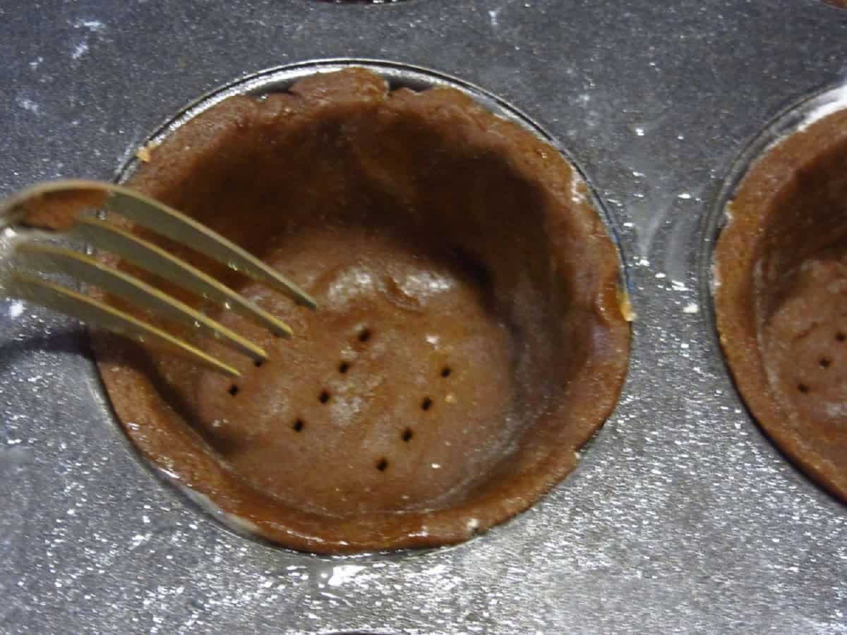 A fork docking holes into gingerbread pie crust.
