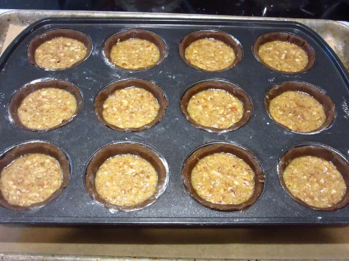Unbaked Gingerbread Pecan Pie Tarts in a muffin tin.