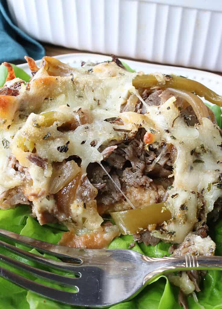 Cheesy beef bread pudding on a plate with a fork.