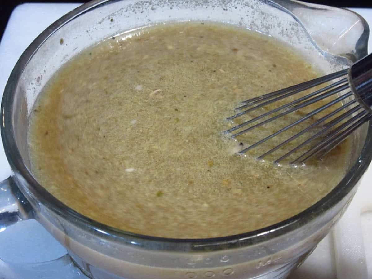 Whisked eggs and beef gravy in a glass bowl with a whisk.