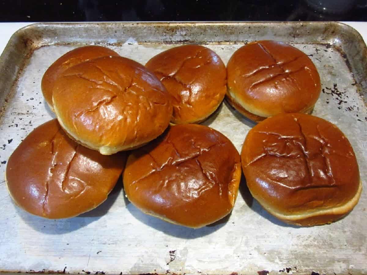 Brioche buns on a baking sheet.