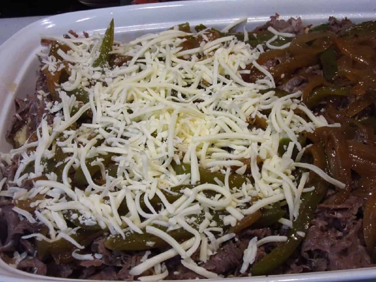 Half shredded cheese and half beef in a casserole dish.