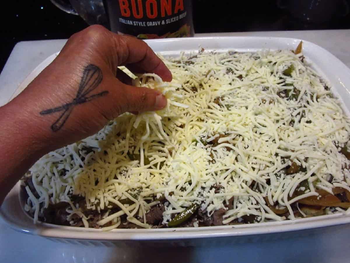 A hand sprinkling cheese on a bread pudding casserole.