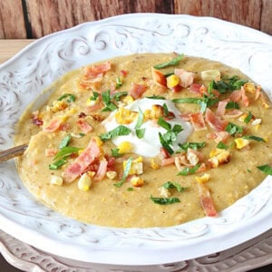 A bowl of roasted corn and potato chowder with sour cream and bacon.