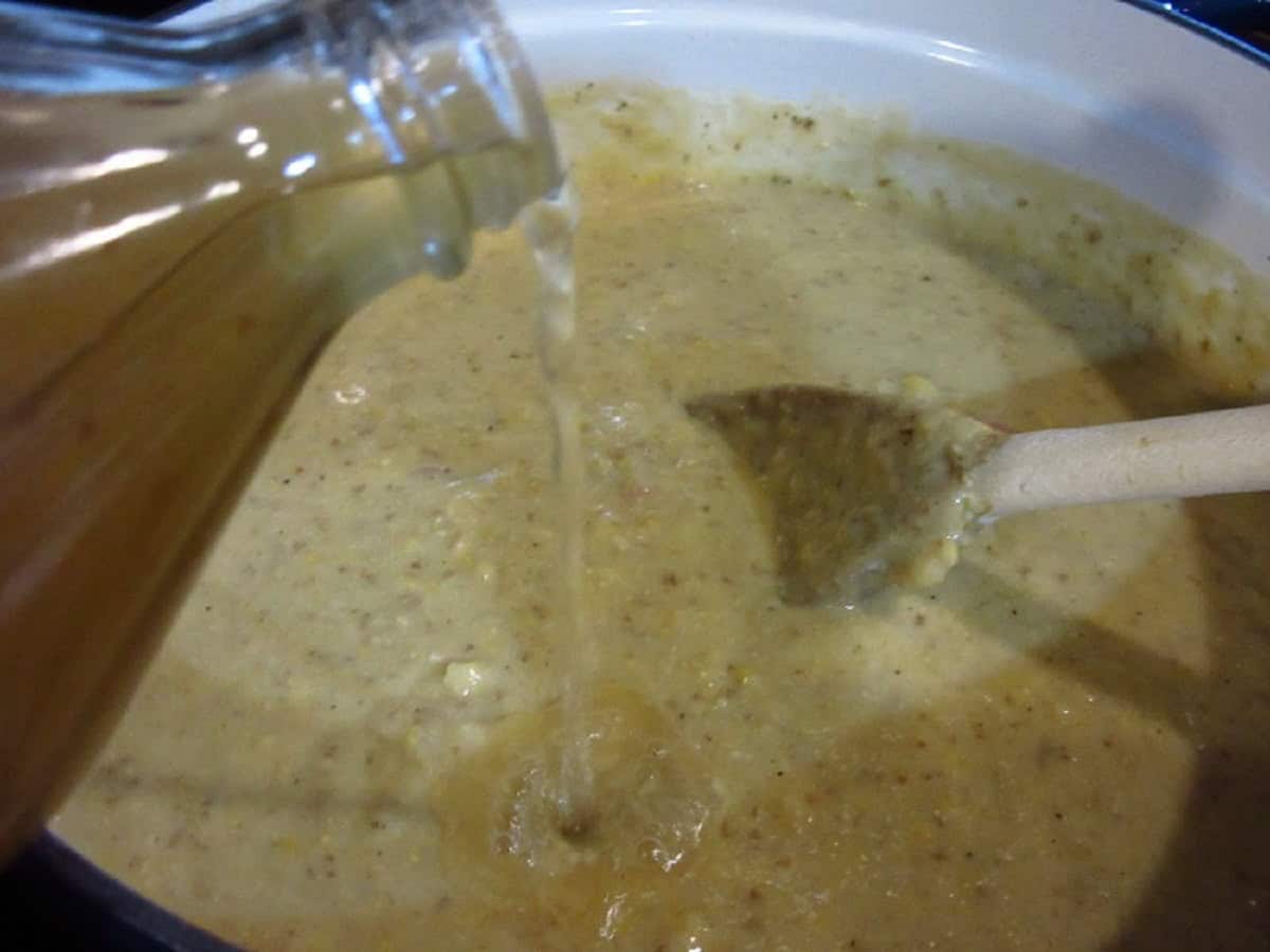 Apple cider vinegar being added to a pot of corn chowder.