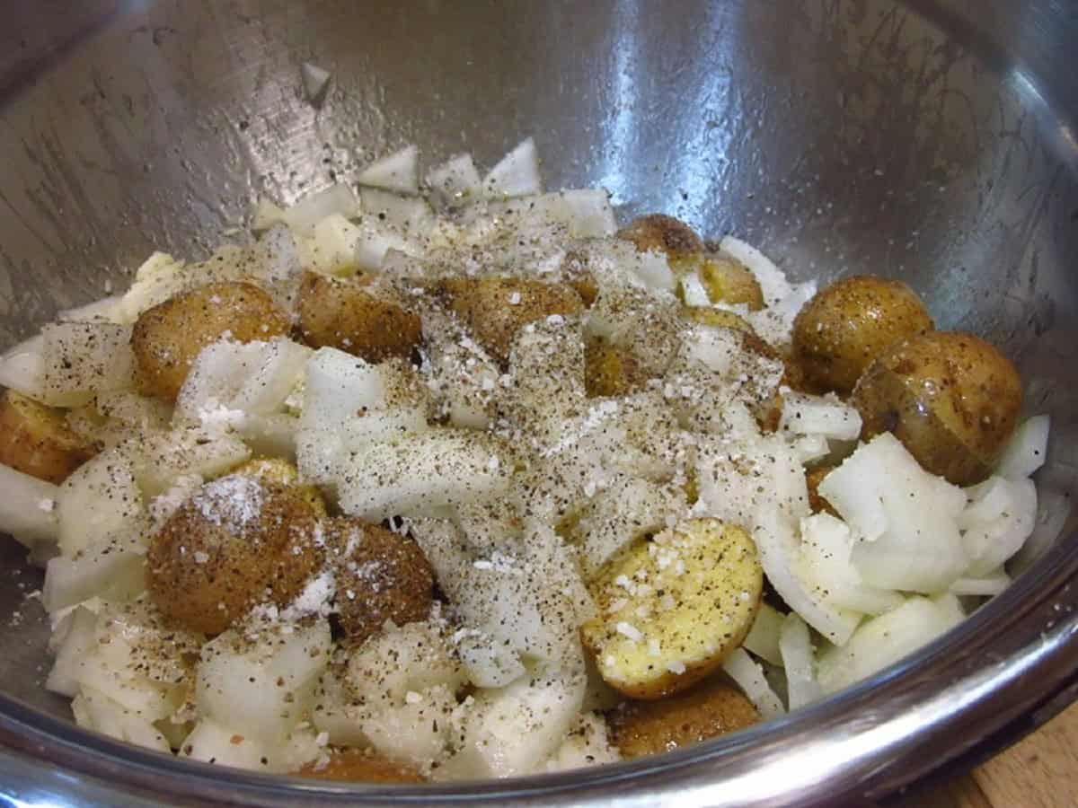 Potatoes, onions, salt and pepper in a large bowl.