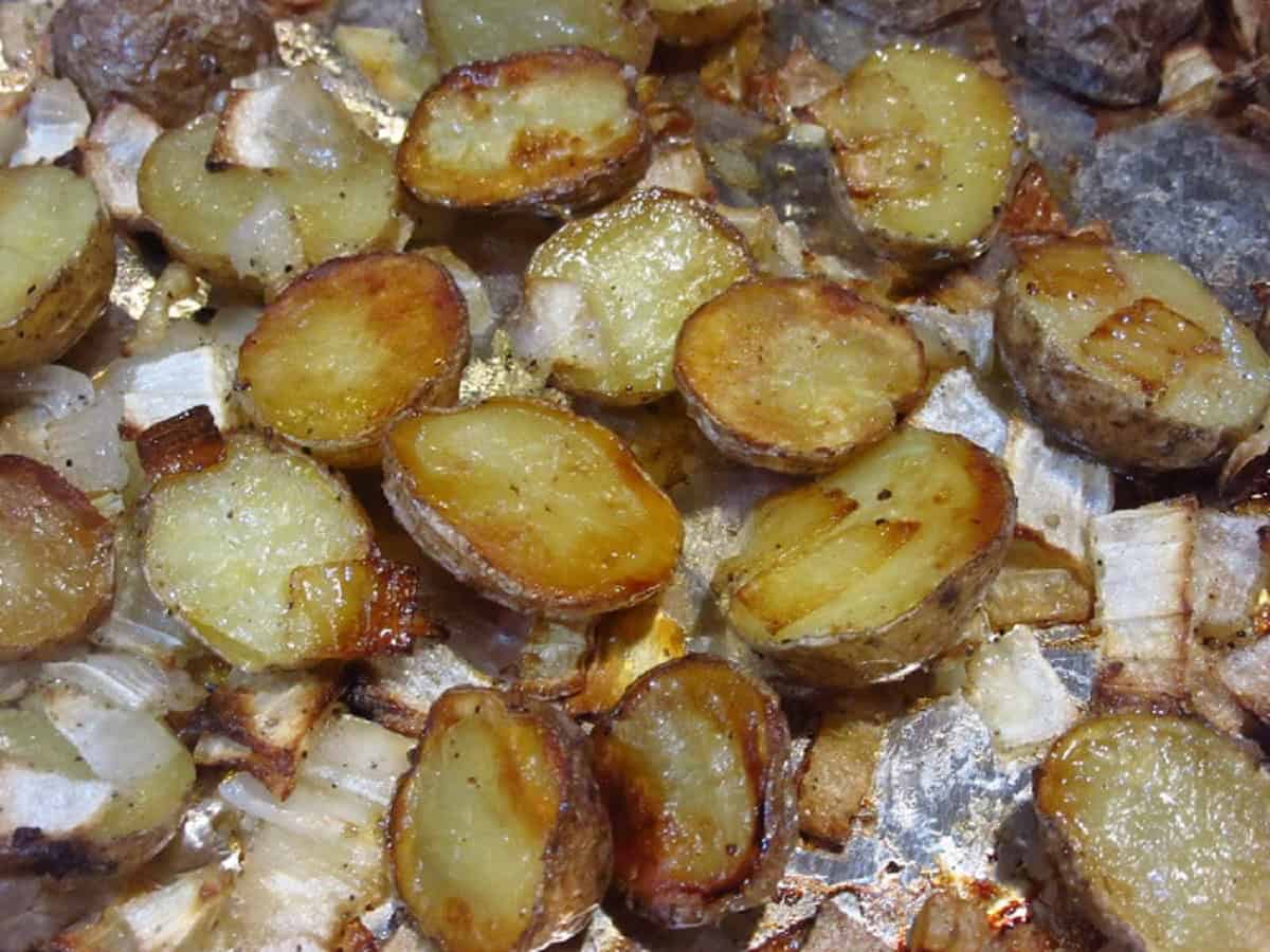 Golden roasted potatoes and onions on a baking sheet.
