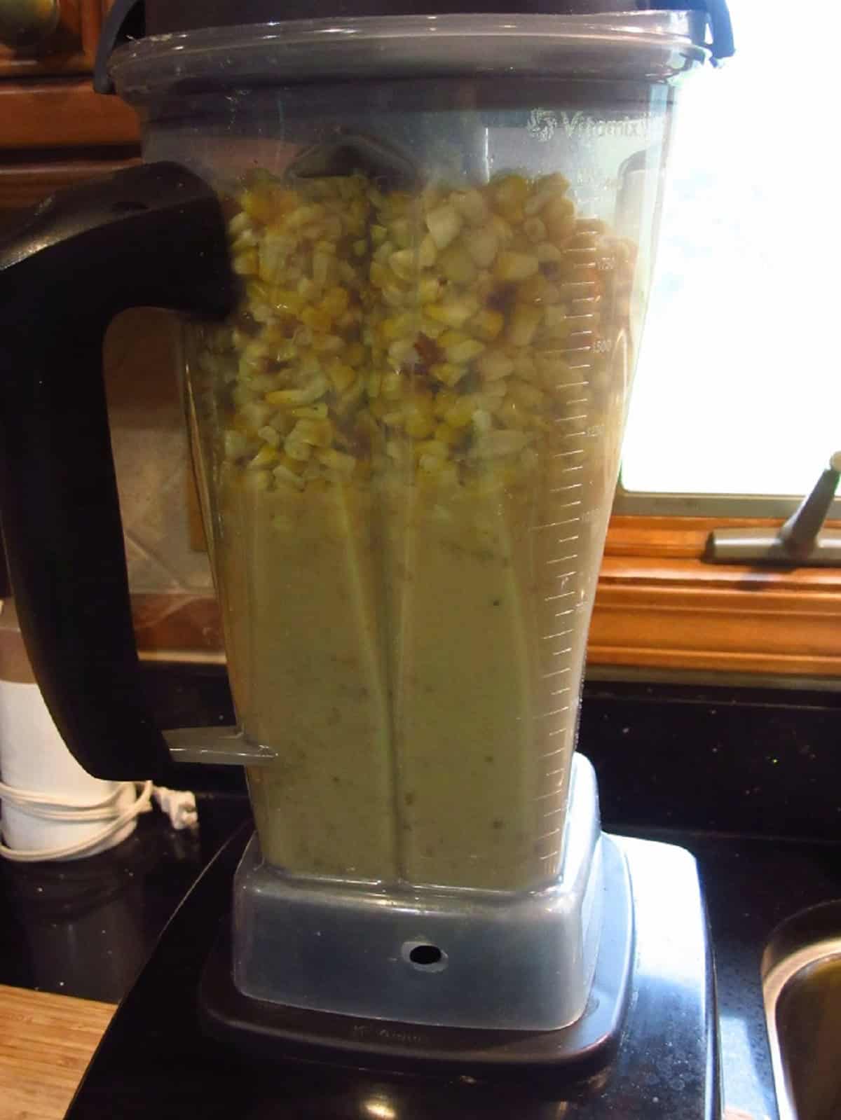 A blender filled with corn and blended chowder.