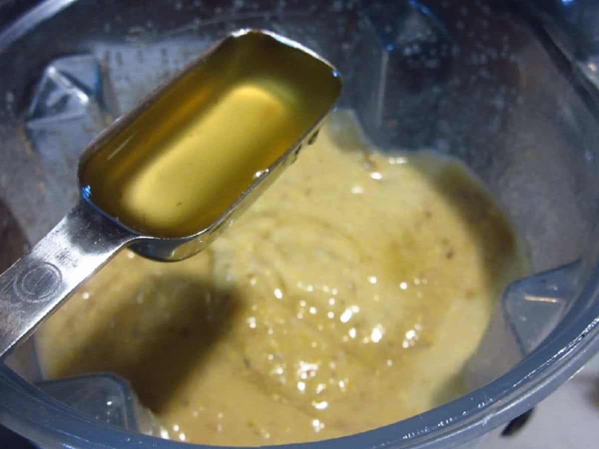 Apple cider being added to a blender with corn chowder.