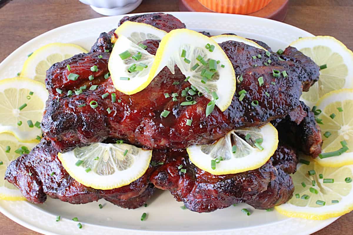 Lemon slices and chives as garnish for glazed spicy roasted BBQ country ribs.