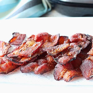 A white plate with a paper towel topped with crispy air fryer bacon.
