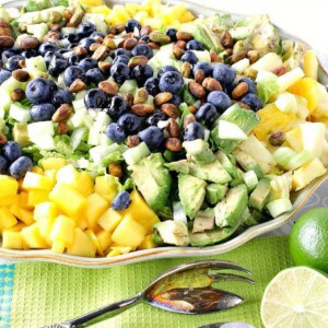 A beautiful avocado mango salad on a platter topped with blueberries.
