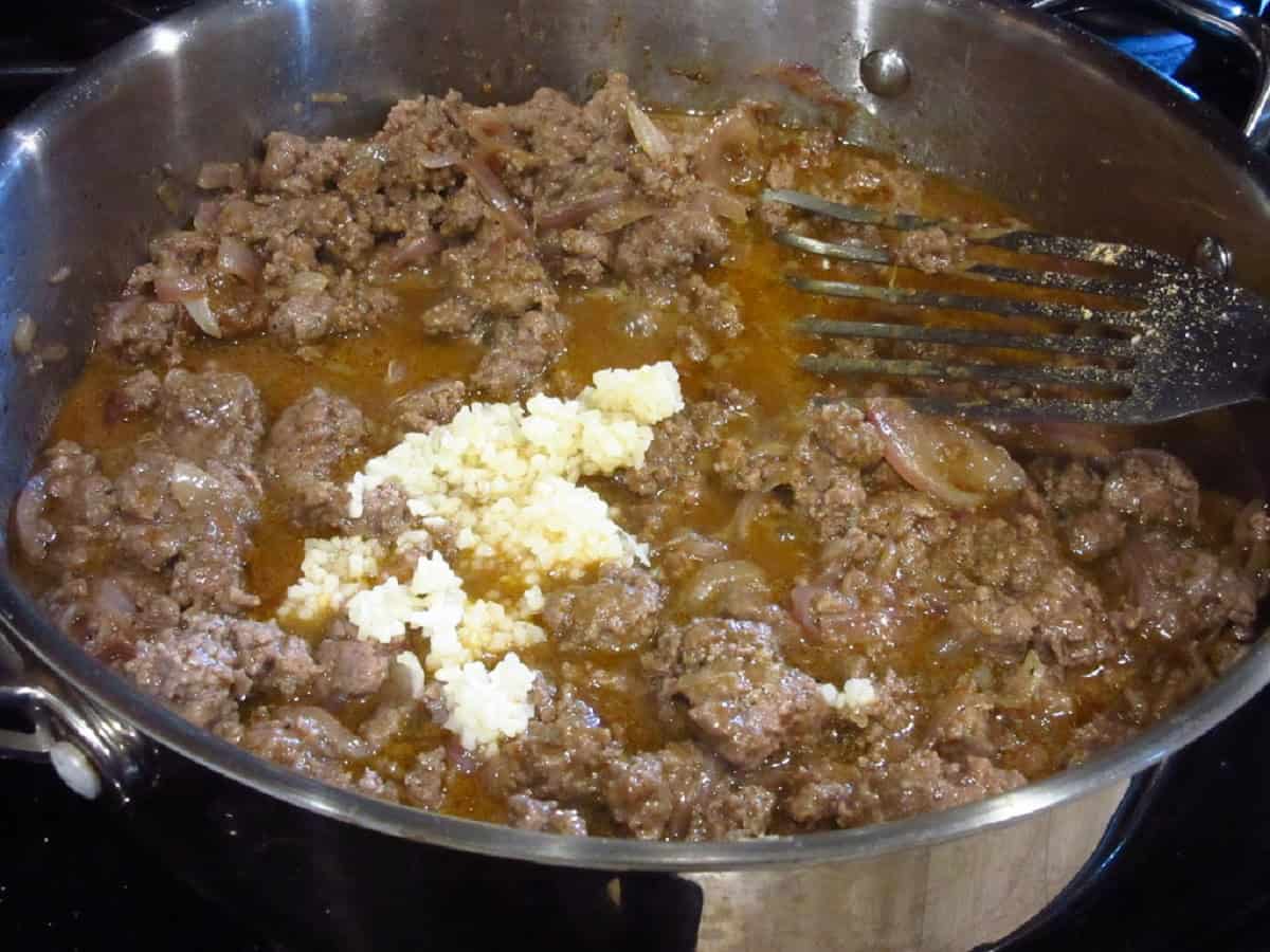 Minced garlic in a skillet of browned ground beef and sauce.