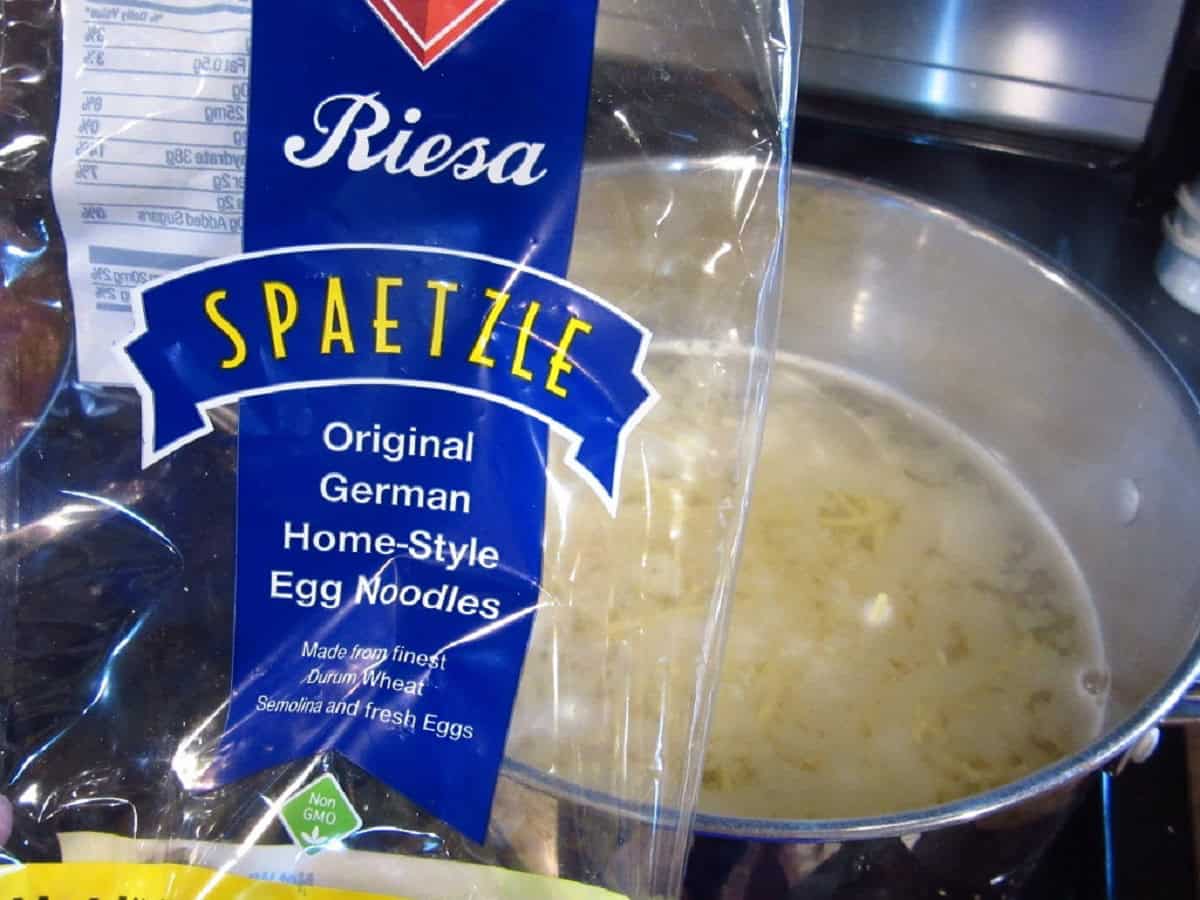 A empty package of spaetzle over a pan of boiling water.