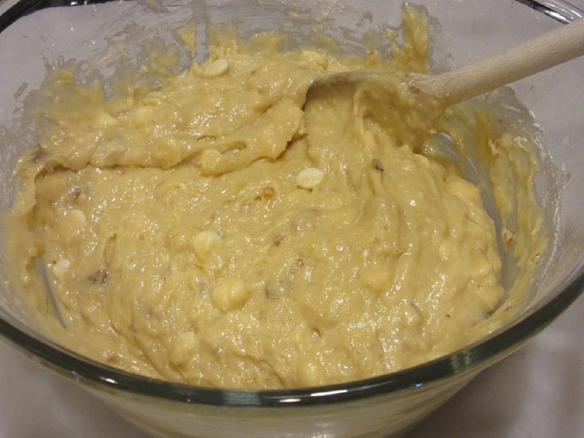 A banana bread batter with white chocolate chips in a glass bowl.