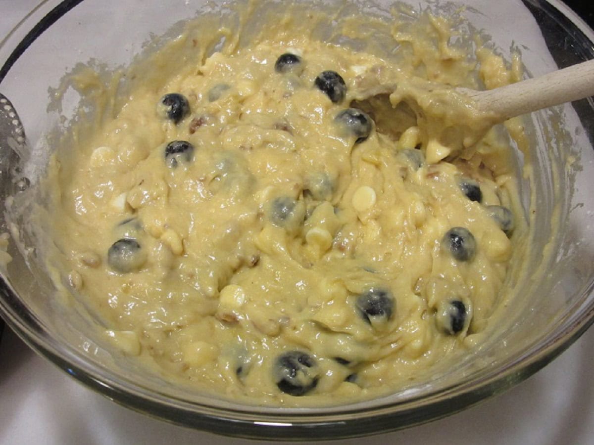 A banana blueberry bread batter with white chocolate in a glass bowl.