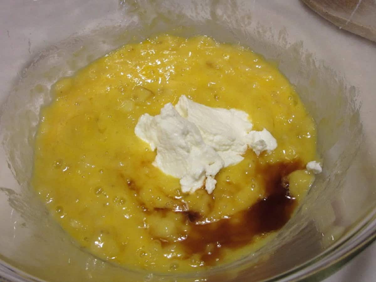 Sour cream in a bowl with mashed bananas, eggs, and vanilla.