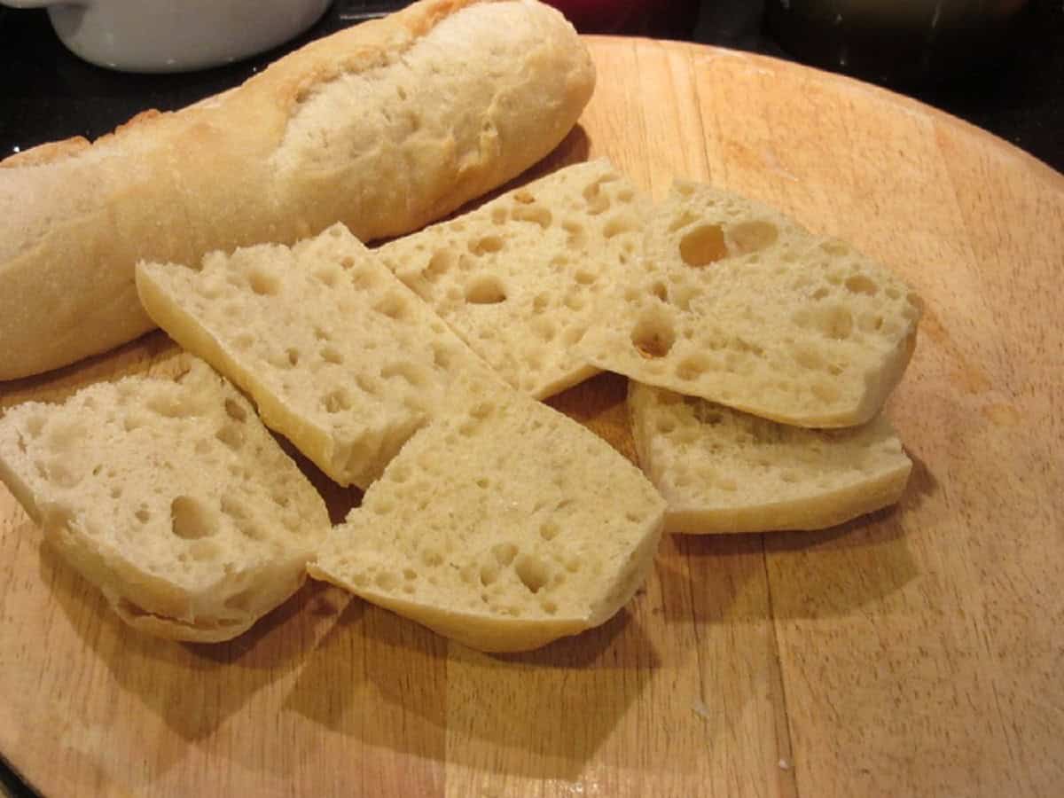 Slices of French bread on a wooden cutting board.