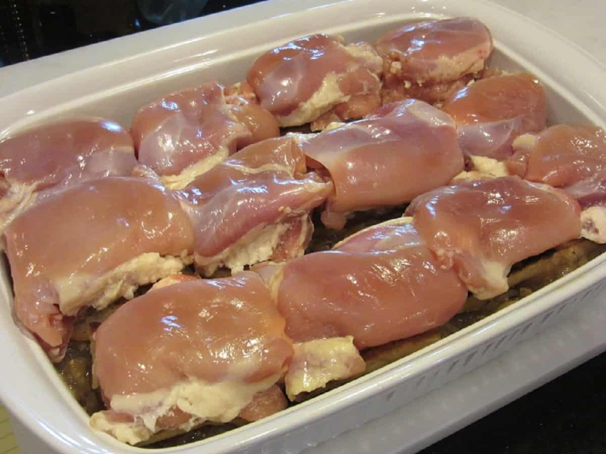 Chicken thighs inside a white casserole dish.