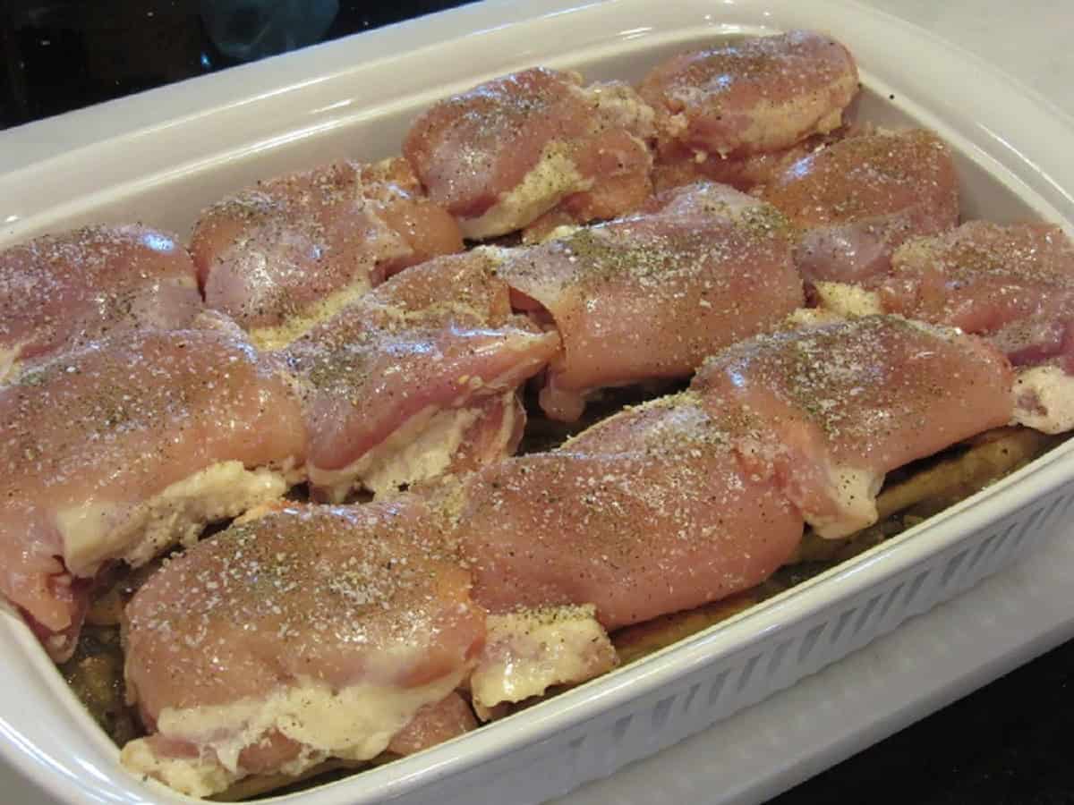 Seasoned chicken thighs in a white rectangle casserole dish.