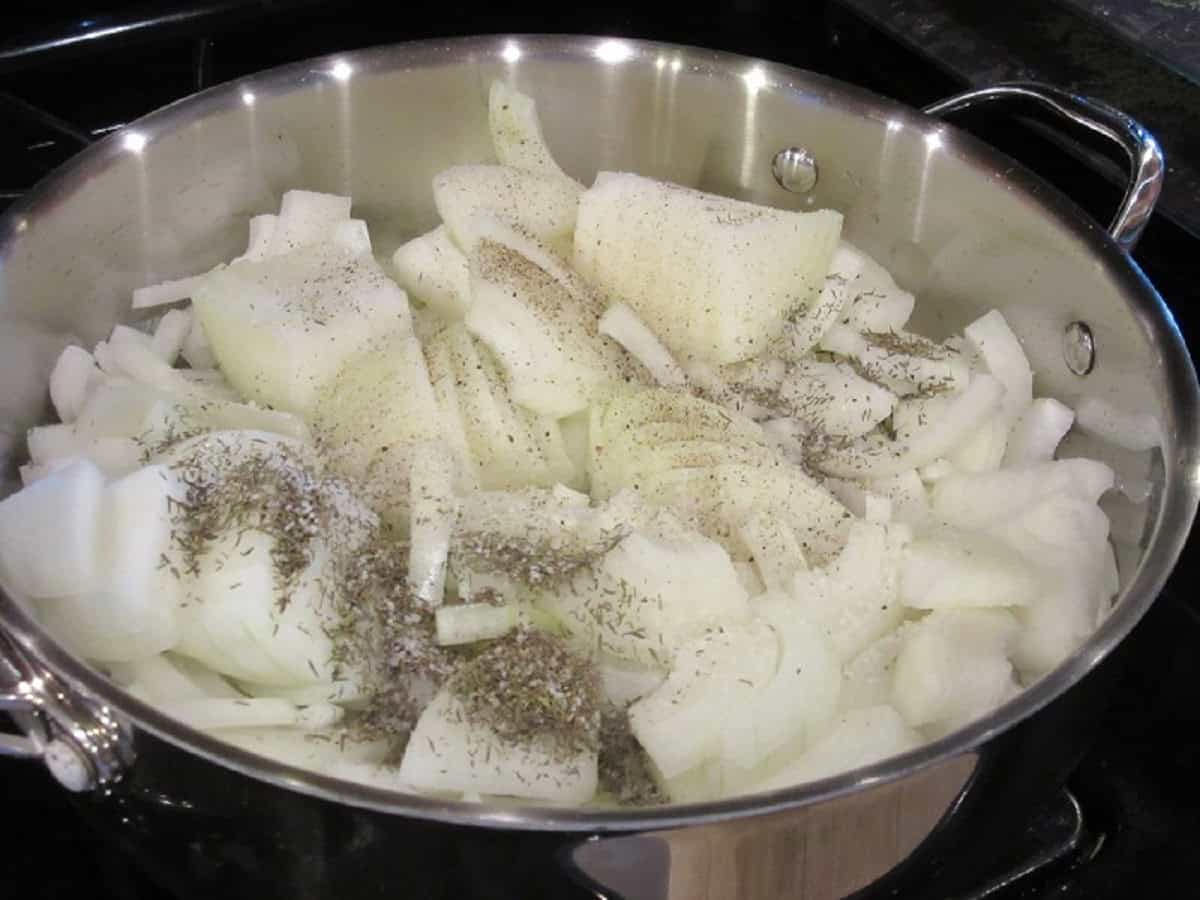 Sliced and seasoned onions in a large skillet.