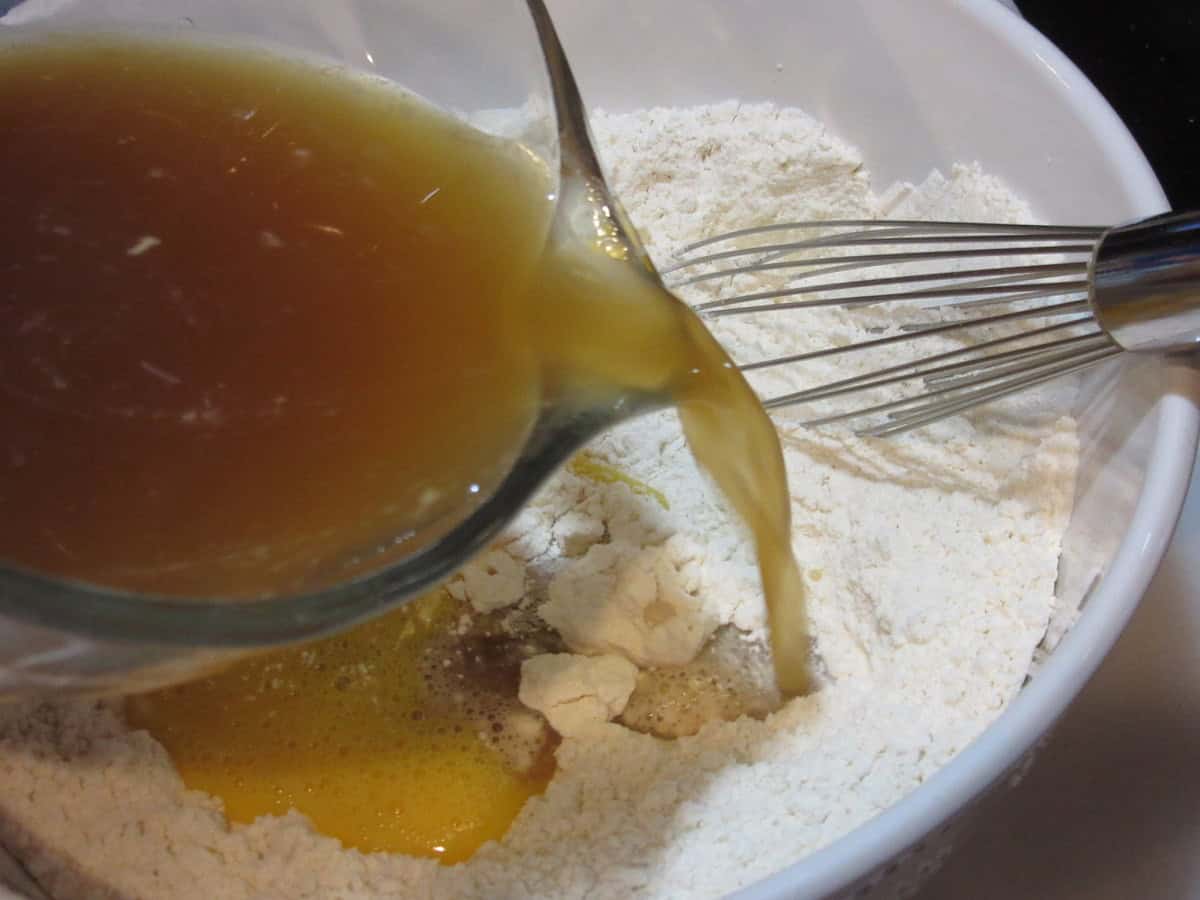 Beef stock being added to a large bowl of flour.