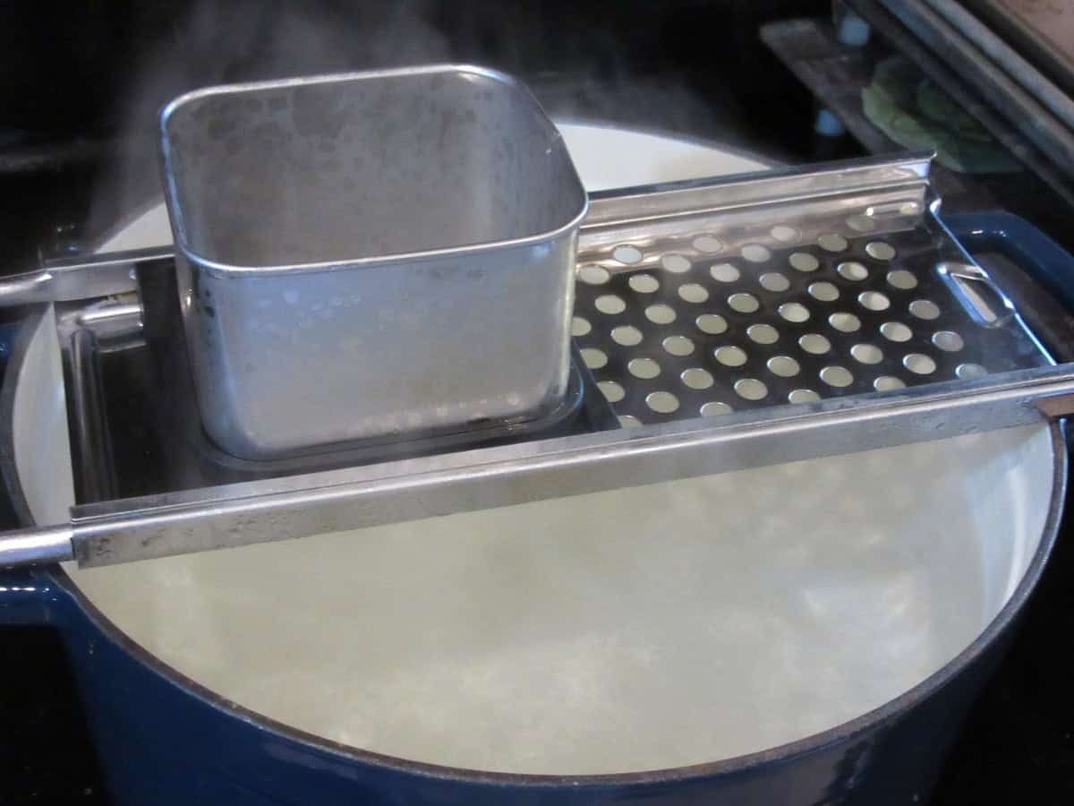 A spaetzle maker over a pot of boiling water.