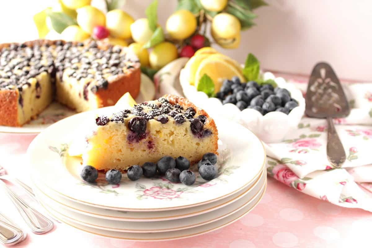 A pretty tablescape with lemon ricotta cake with blueberries along with a pink polka dot tablecloth.