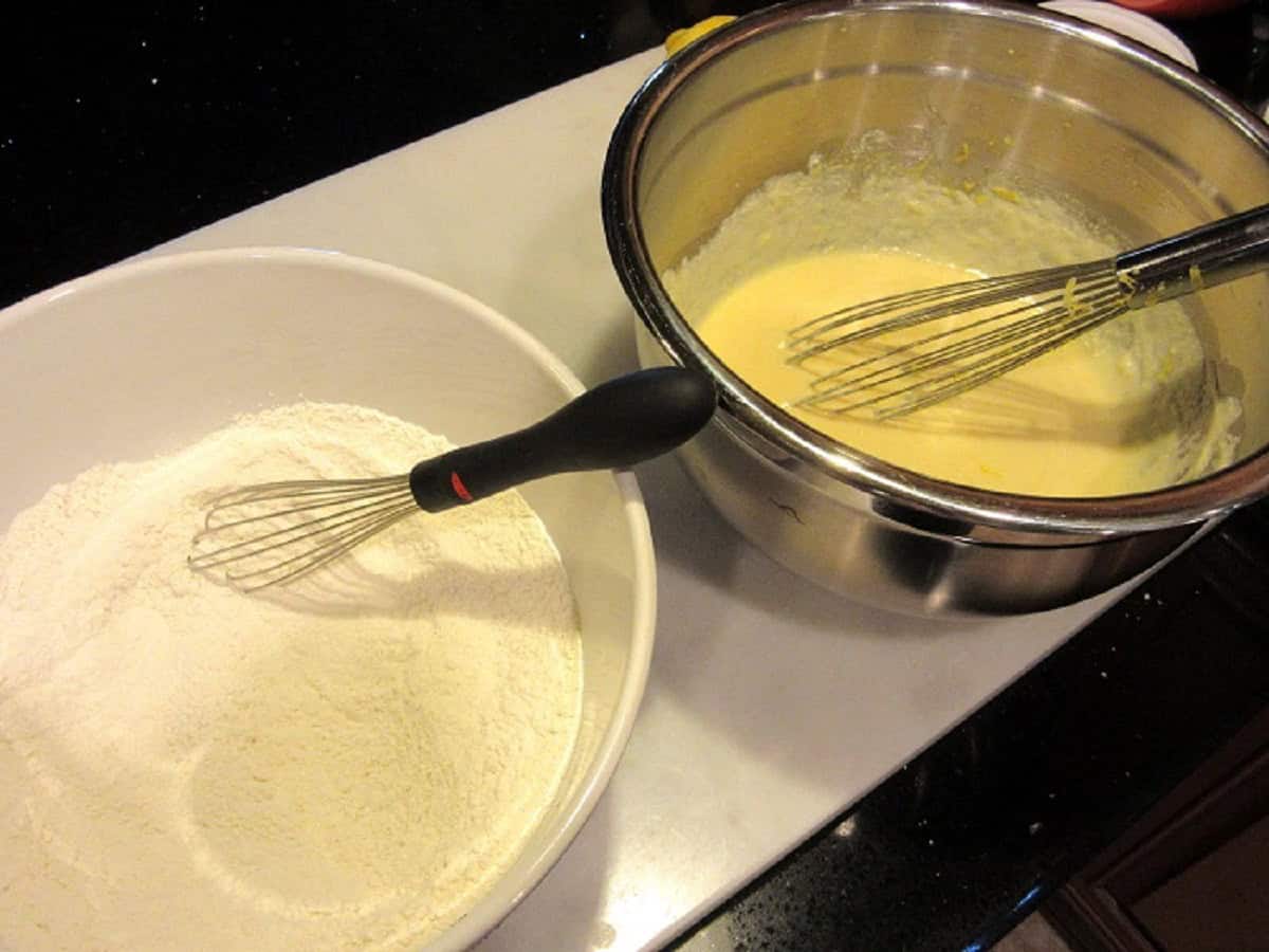 Two bowls with ingredients for making a lemon ricotta cake.