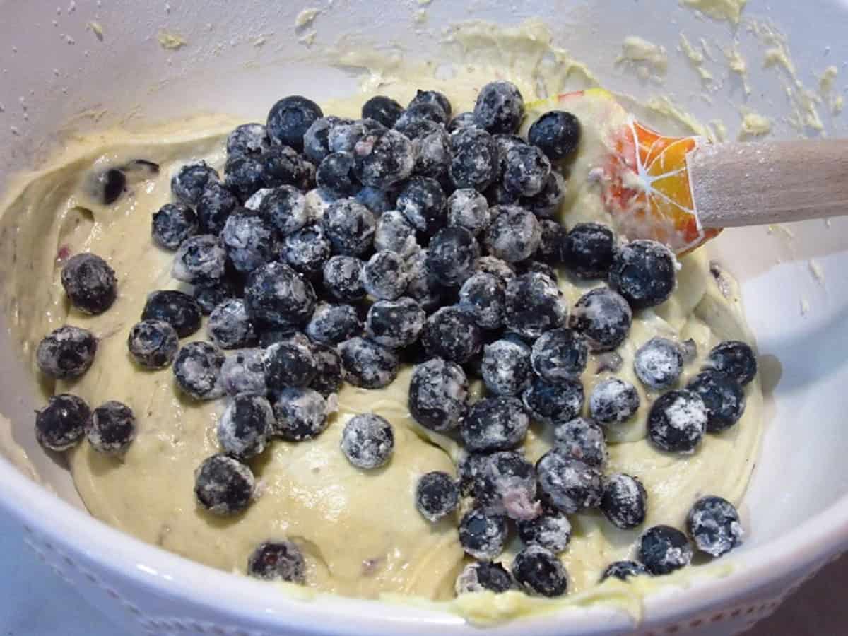 Floured blueberries being mixed into a blueberry muffin batter.